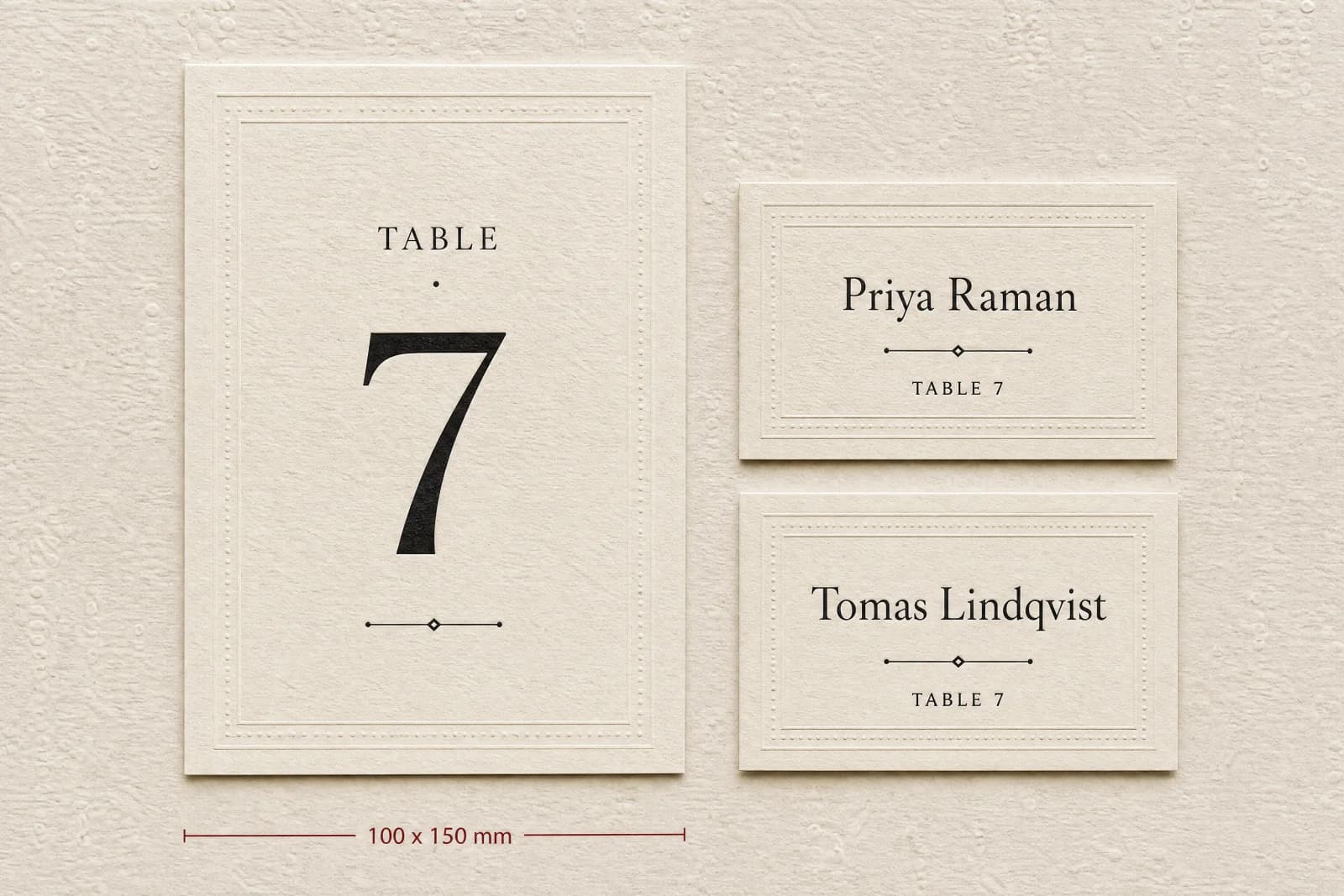A large table number card standing beside two smaller place cards in the same design system